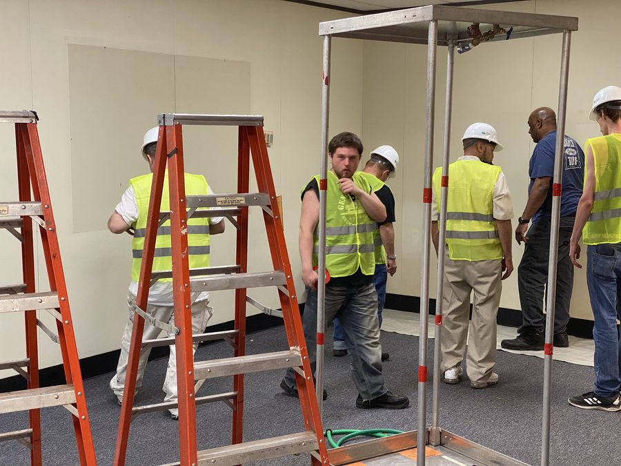 Apprentices assemble the three-stage decon unit under supervision.